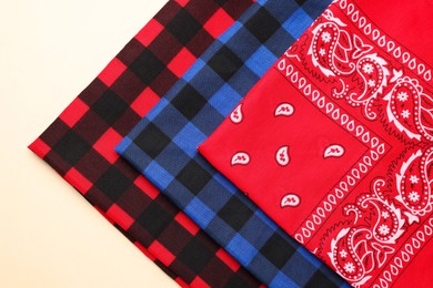 Photo of Folded bandanas with different patterns on beige background, flat lay