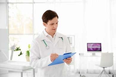 Young male doctor with clipboard in hospital. Gynecology consultation