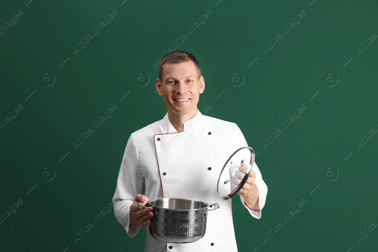 Photo of Happy male chef with cooking pot on dark green background