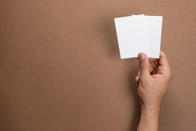 Photo of Man holding sheets of paper on brown background, closeup. Mockup for design