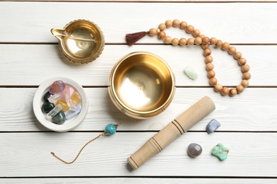 Flat lay composition with golden singing bowl on white wooden table. Sound healing