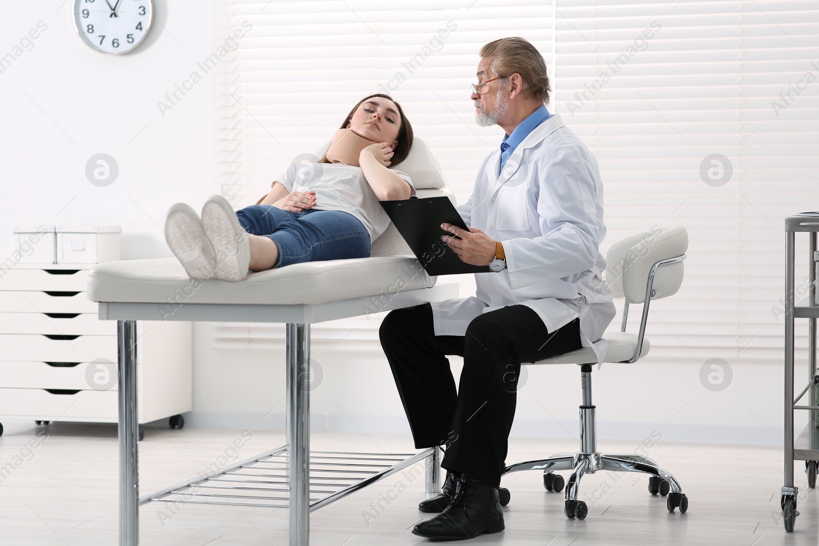 Photo of Orthopedist examining patient with injured neck in clinic