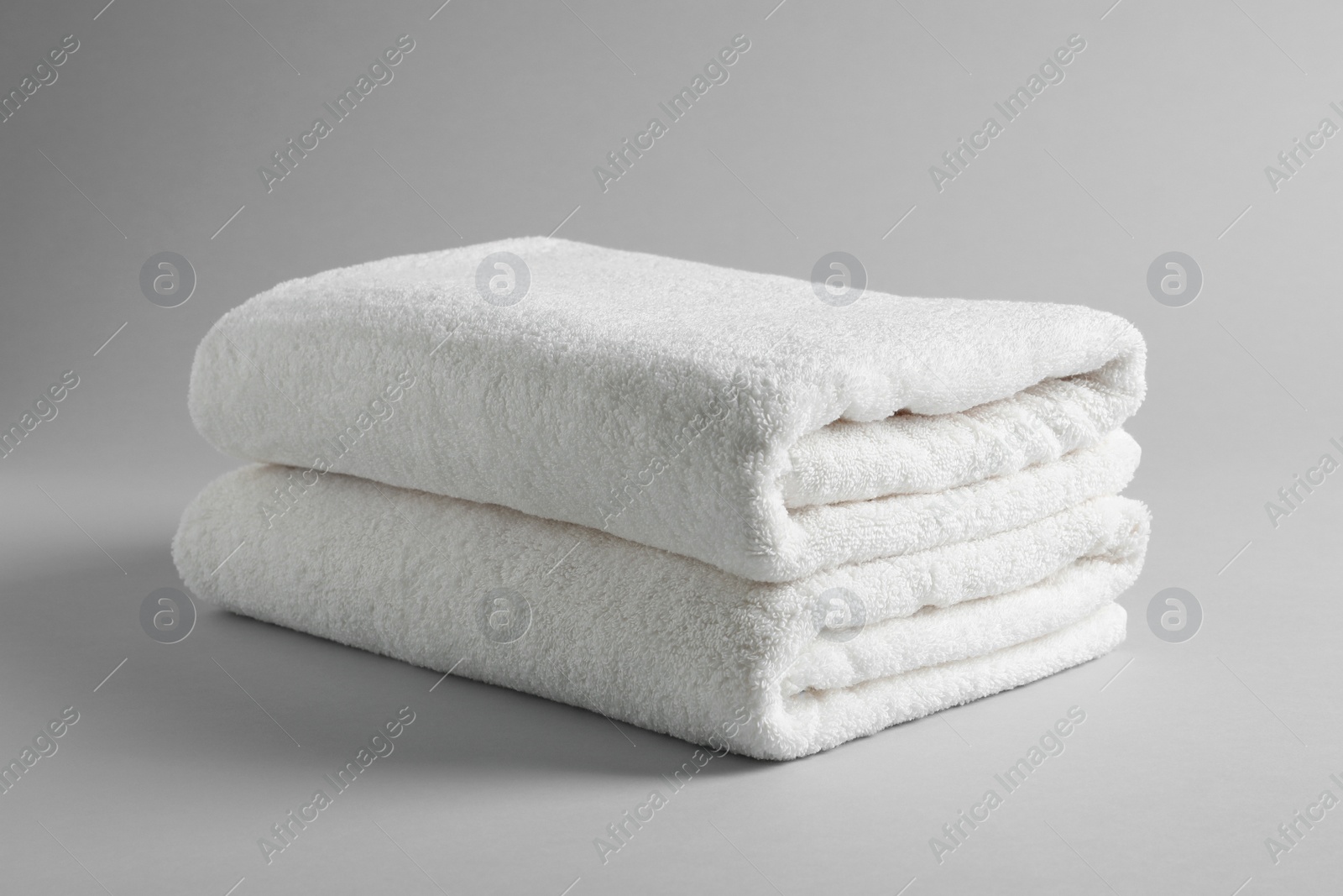 Photo of Fresh soft folded towels on light background