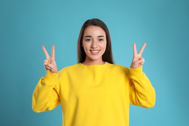 Photo of Woman showing number four with her hands on light blue background