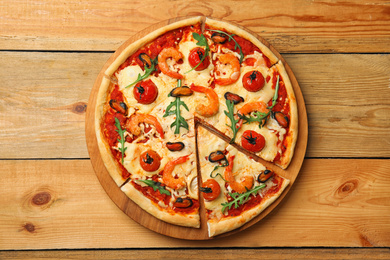 Delicious seafood pizza on wooden table, top view