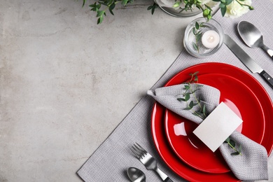 Elegant festive table setting with blank card on grey background, flat lay. Space for text