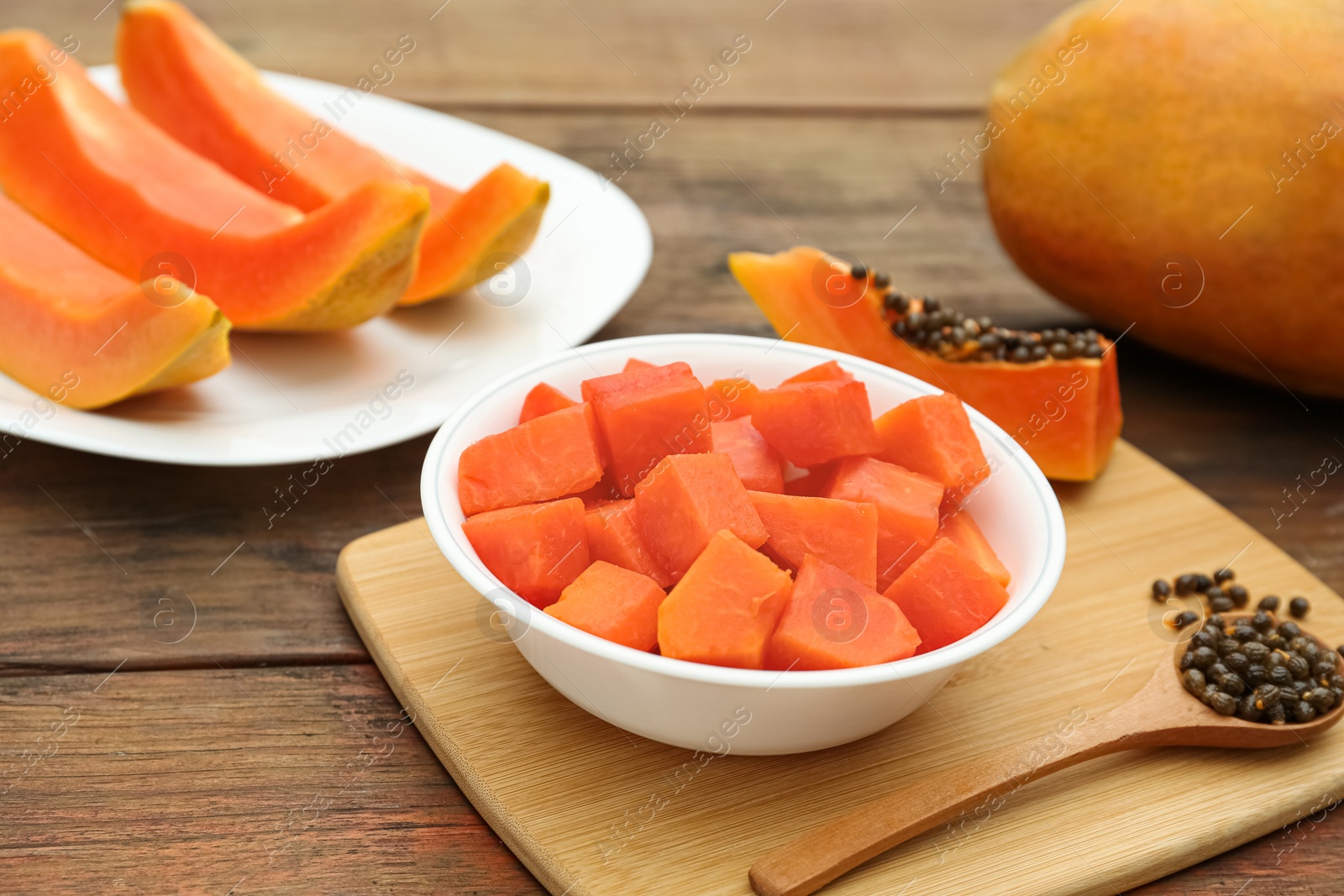 Photo of Tasty cut and whole papaya fruits on wooden table