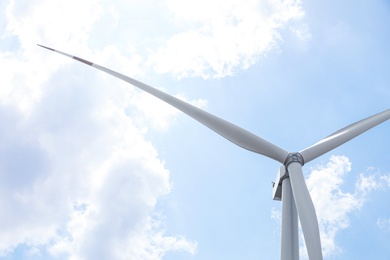 Modern wind turbine against blue sky, low angle view. Energy efficiency