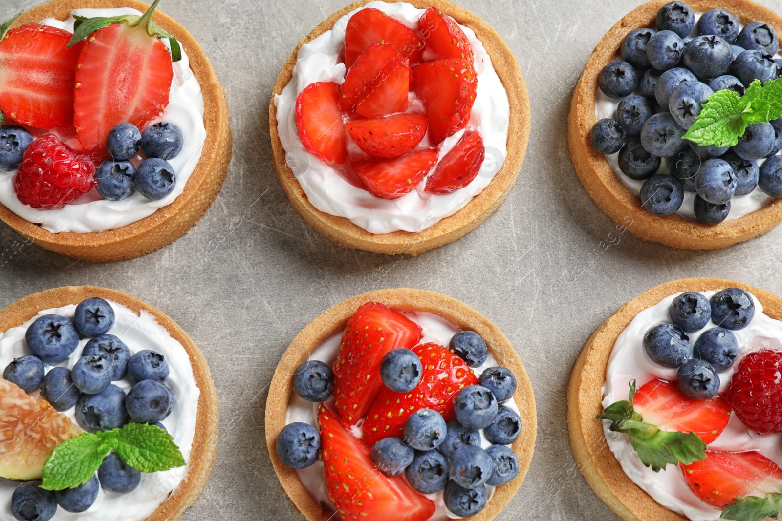 Photo of Delicious sweet pastries with berries on grey table, flat lay