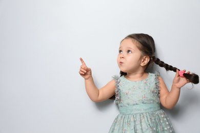 Photo of Cute little girl on light grey background. Space for text