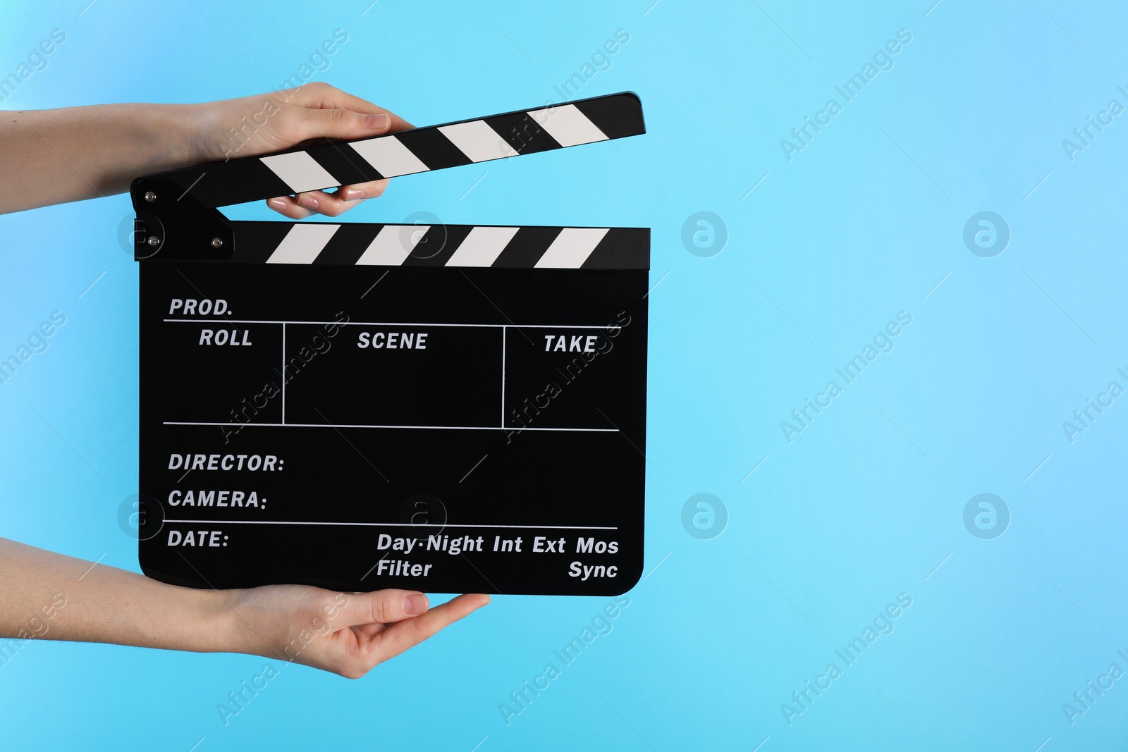 Photo of Woman holding movie clapper on light blue background, closeup. Space for text