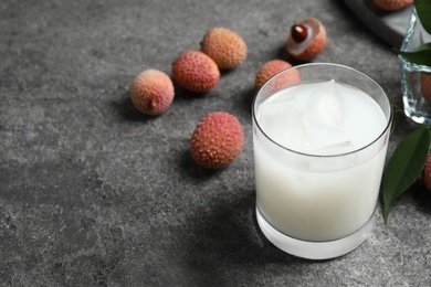 Lychee juice and fresh fruits on grey table. Space for text