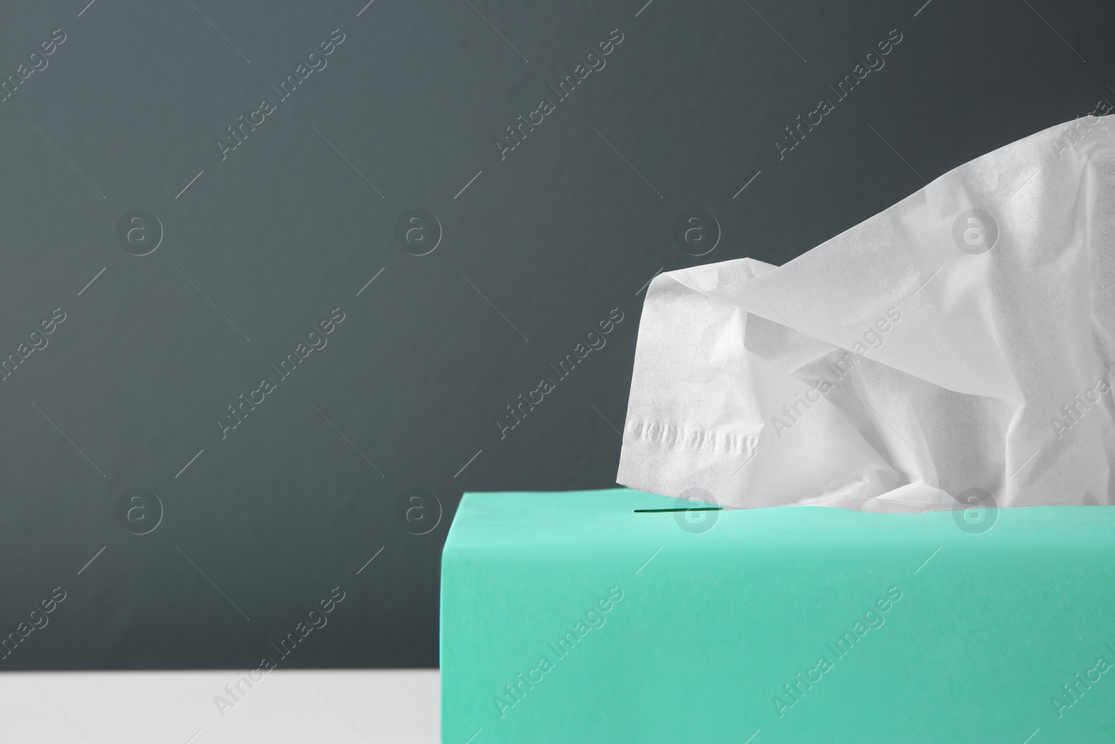 Photo of Box with paper tissues on table against black background, closeup. Space for text