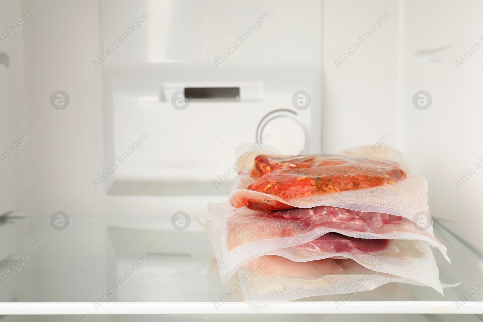 Photo of Vacuum bags with different products in fridge, space for text. Food storage