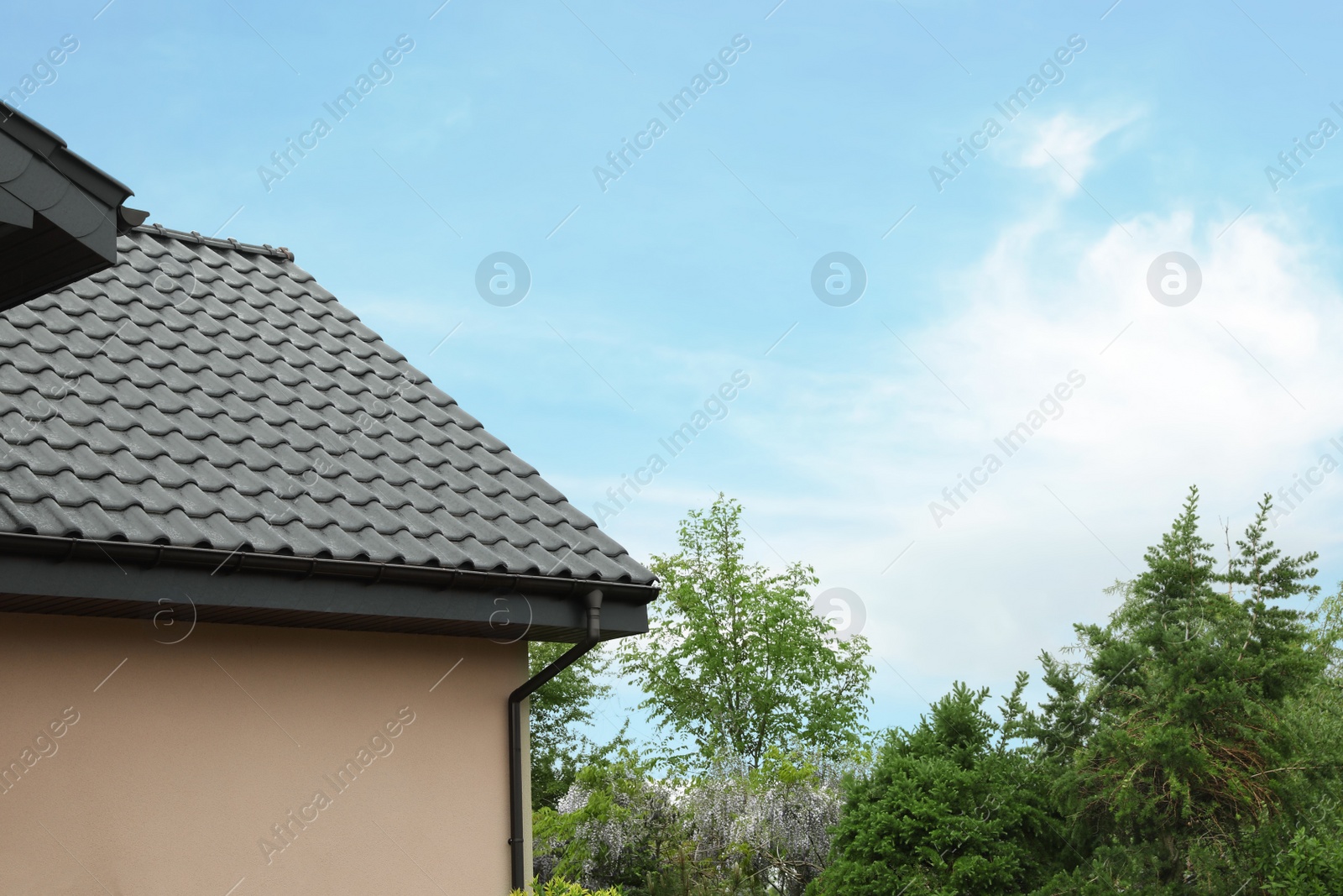 Photo of Beautiful house with grey roof against blue sky