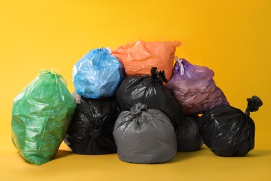 Trash bags full of garbage on yellow background