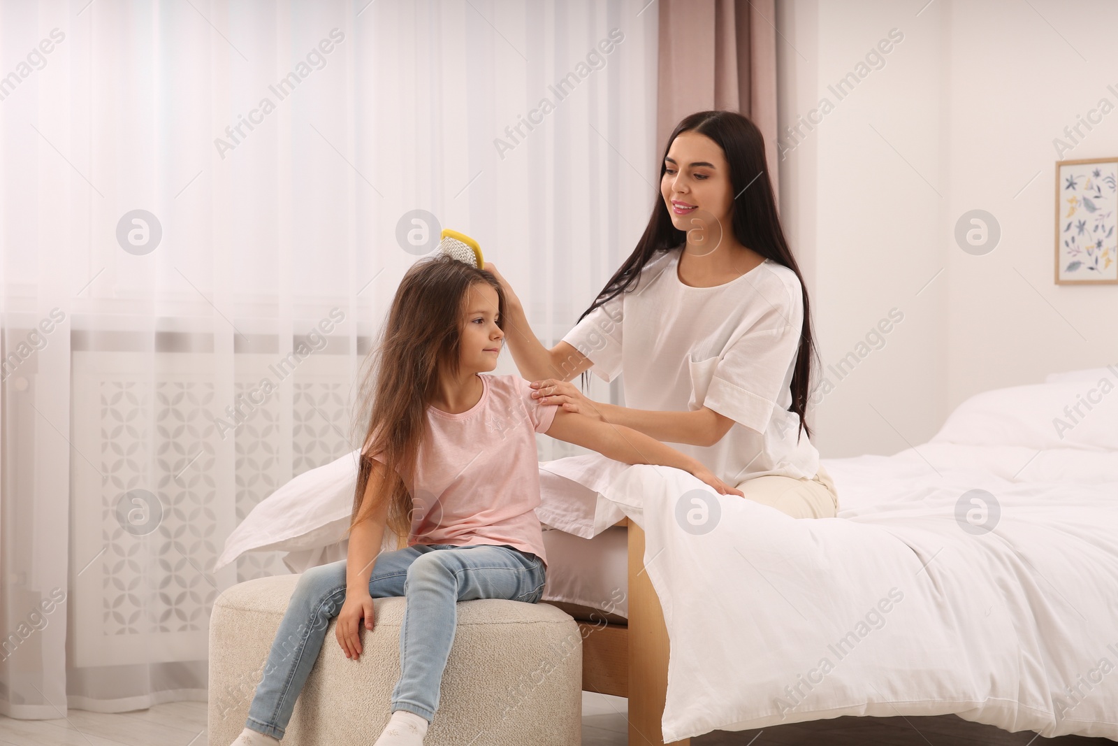 Photo of Happy woman and her daughter spending time together on bed at home. Mother's day celebration