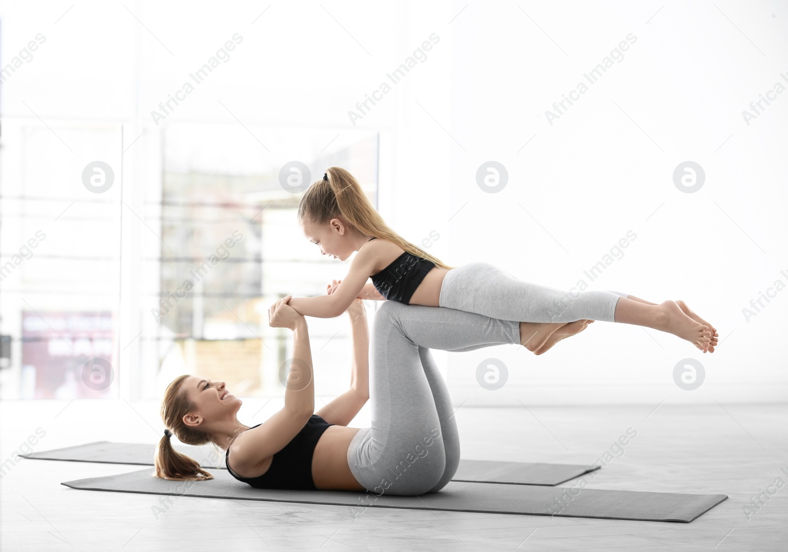 Photo of Mother and daughter in matching sportswear doing yoga together at home