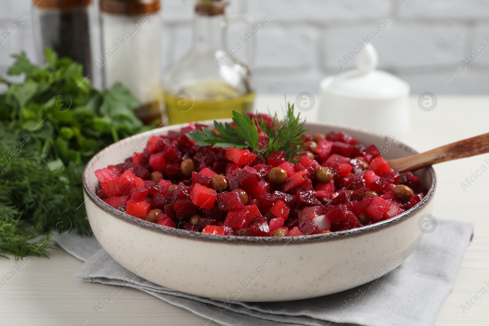 Photo of Bowl of delicious fresh vinaigrette salad on white wooden table, closeup