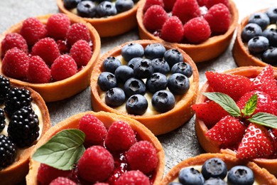 Photo of Tartlets with different fresh berries on table, closeup. Delicious dessert