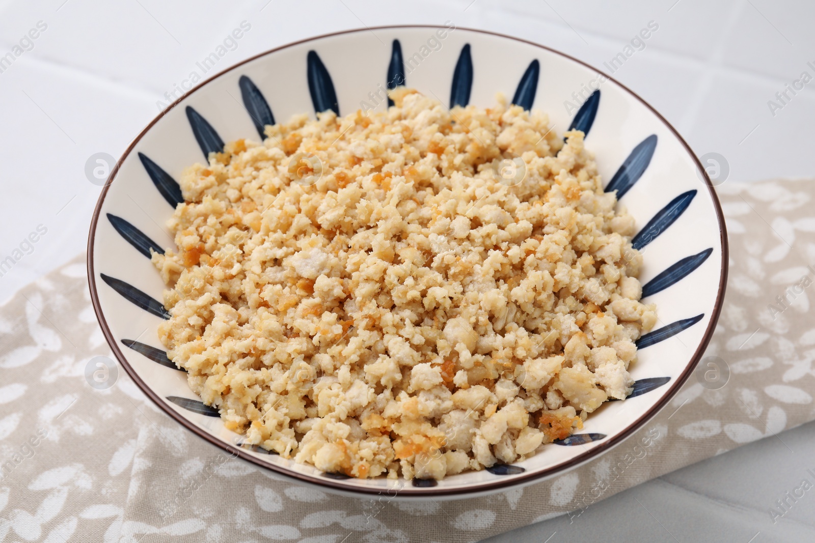 Photo of Fried ground meat in bowl on white tiled table, closeup