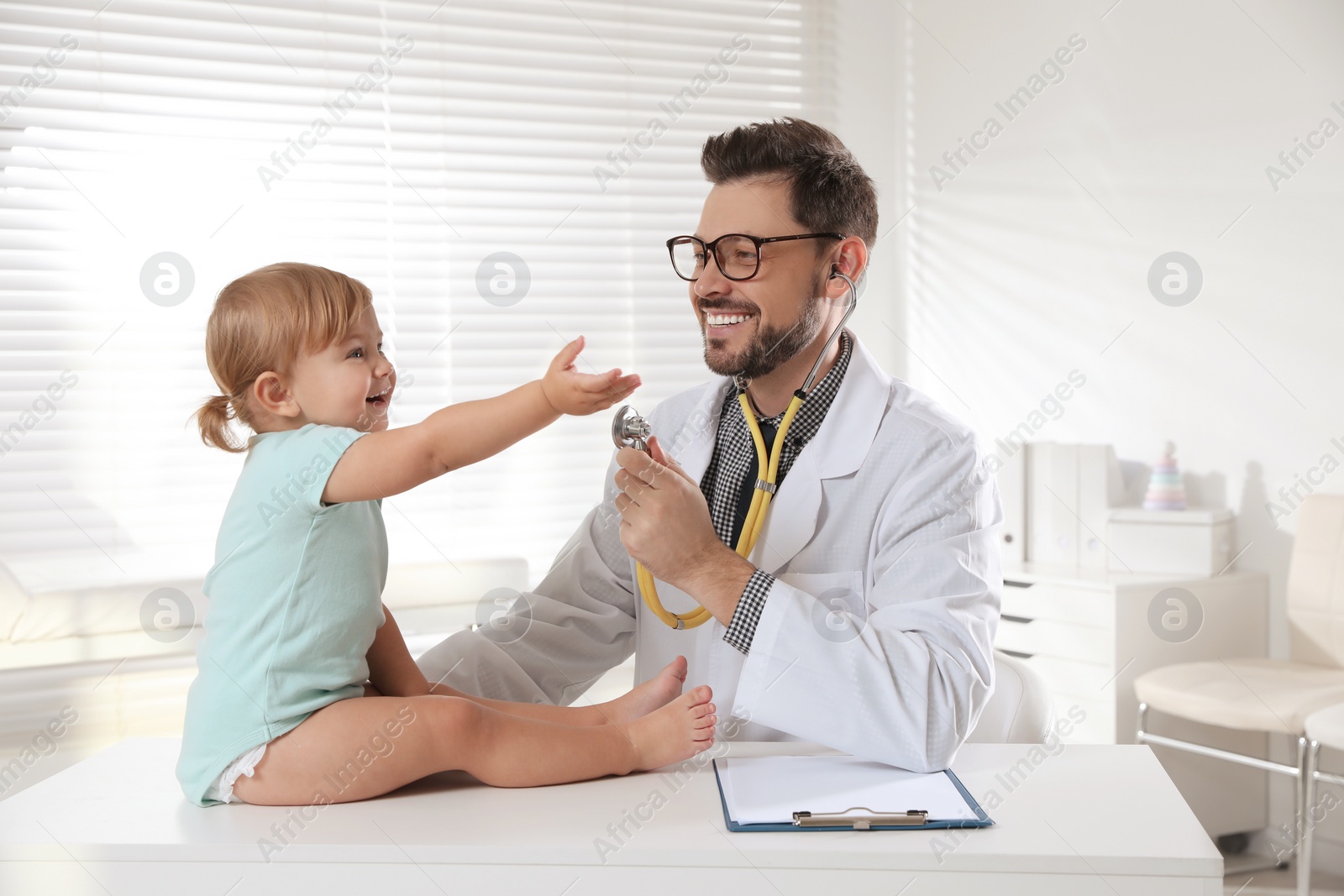 Photo of Pediatrician examining cute little baby in clinic