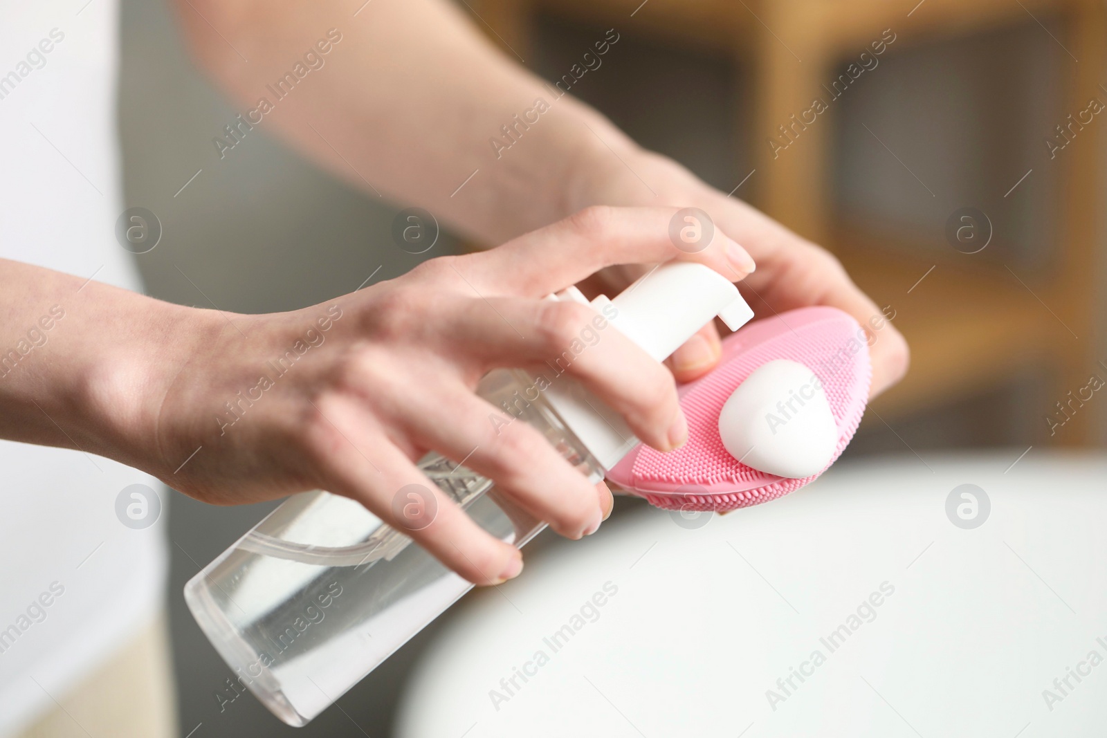 Photo of Washing face. Woman applying cleansing foam onto brush in bathroom, closeup