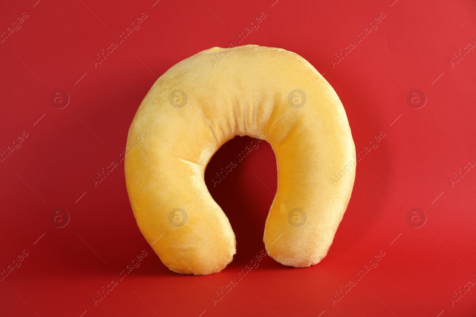 Photo of One yellow travel pillow on red background