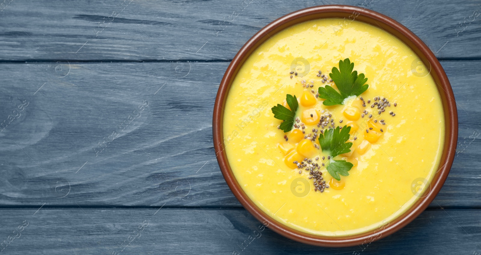 Photo of Delicious creamy corn soup on blue wooden table, top view Space for text