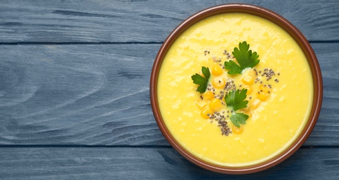 Delicious creamy corn soup on blue wooden table, top view Space for text