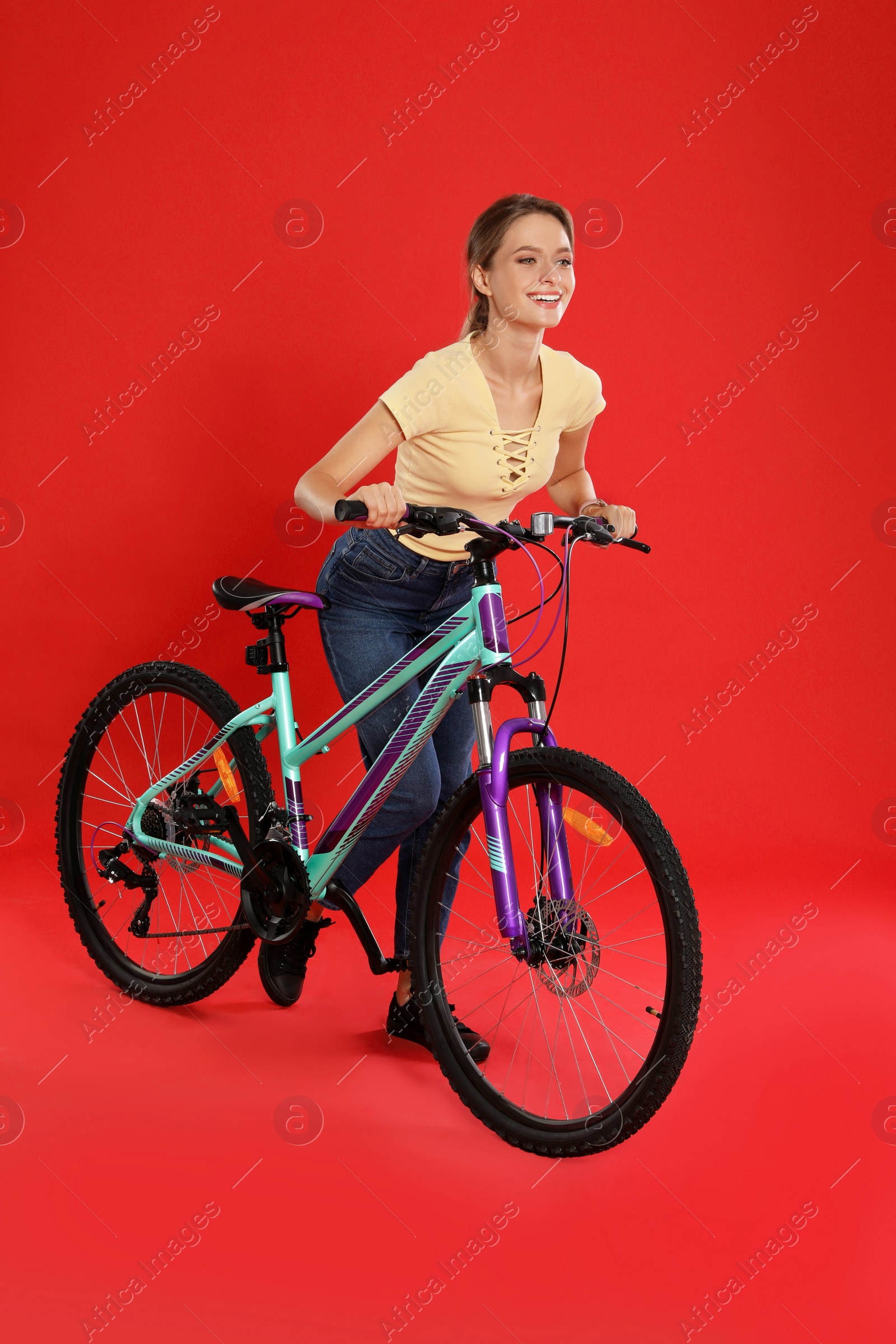 Photo of Happy young woman with bicycle on red background