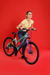 Photo of Happy young woman with bicycle on red background