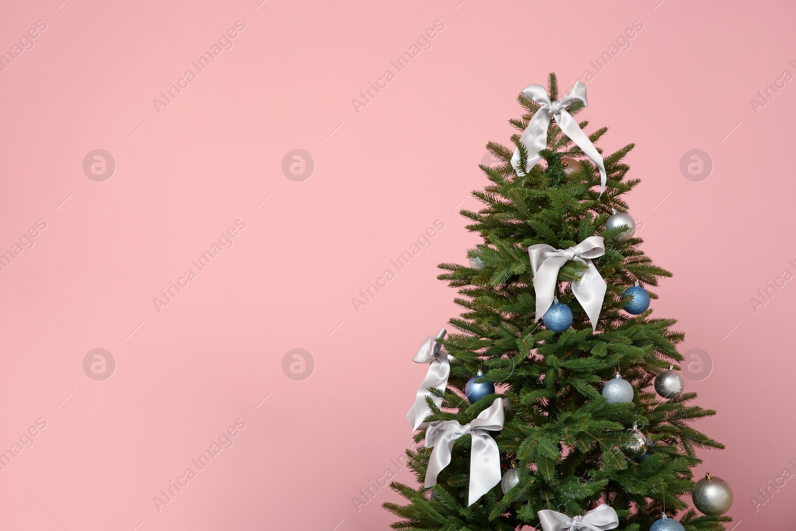 Photo of Beautifully decorated Christmas tree on color background