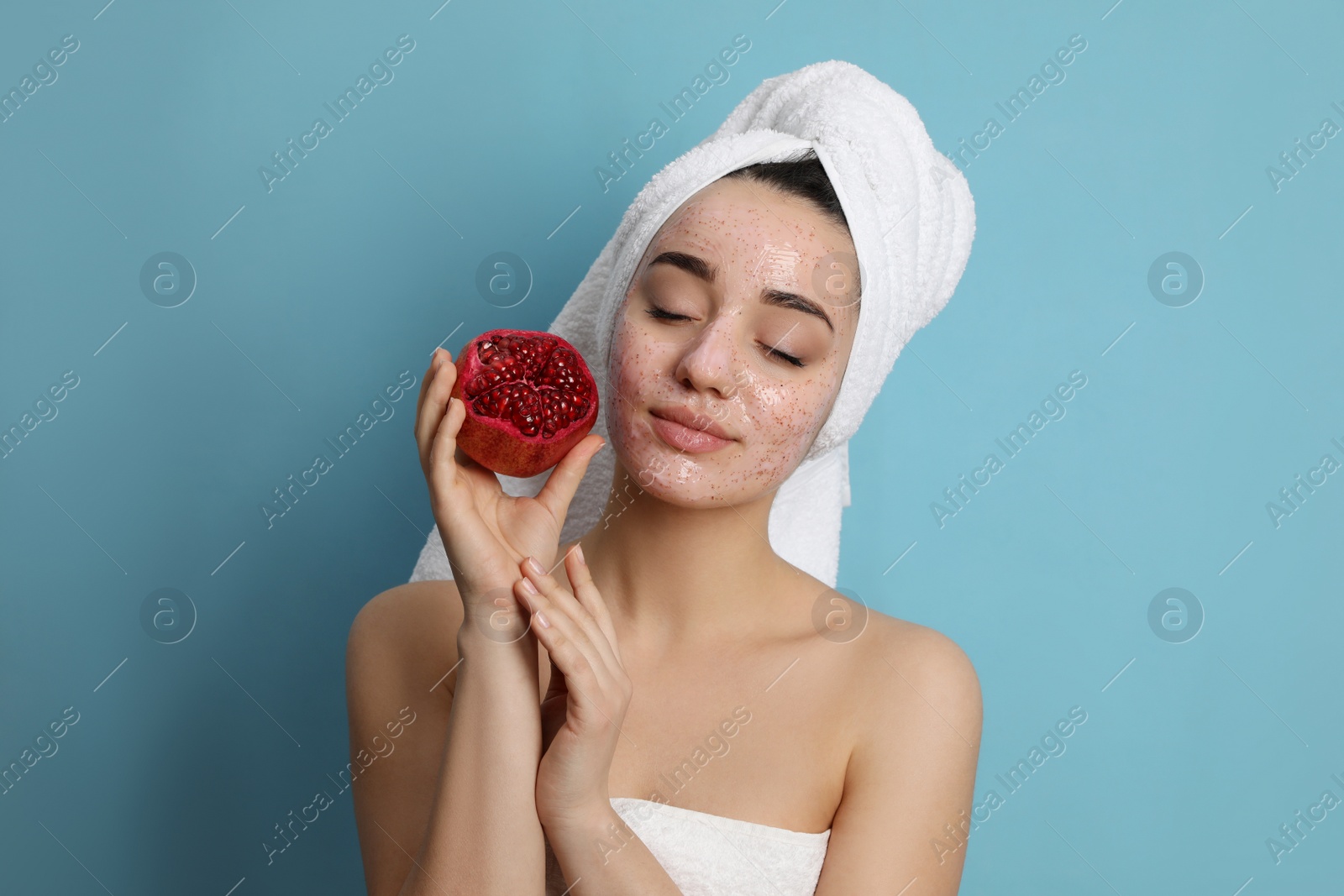 Photo of Woman with pomegranate face mask and fresh fruit on light blue background