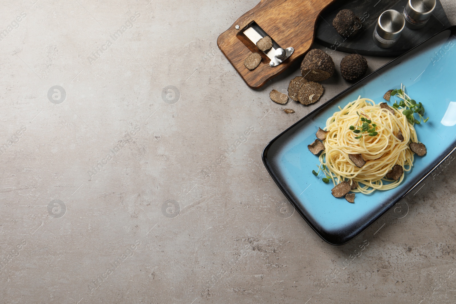 Photo of Delicious pasta with truffle slices and microgreens served on light grey table, flat lay. Space for text