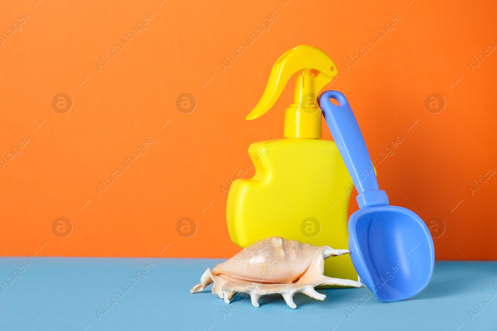 Photo of Suntan product, seashell and plastic beach toy on color background. Space for text