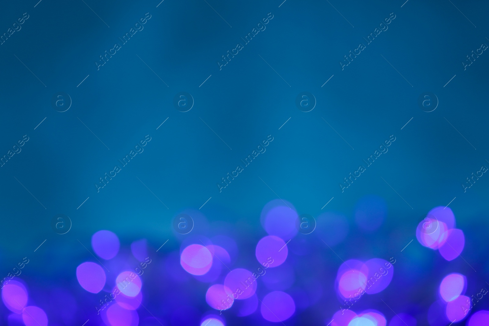 Photo of Blurred violet Christmas lights against blue background