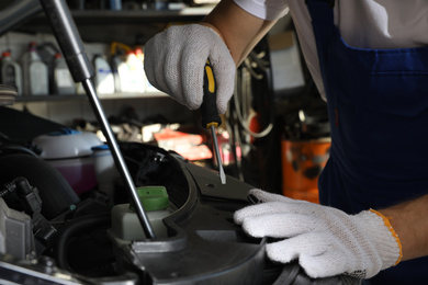 Photo of Professional auto mechanic fixing modern car in service center, closeup