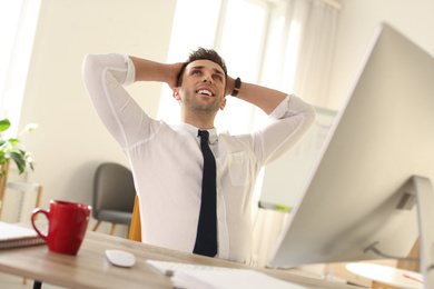 Photo of Young businessman relaxing at table in office during break