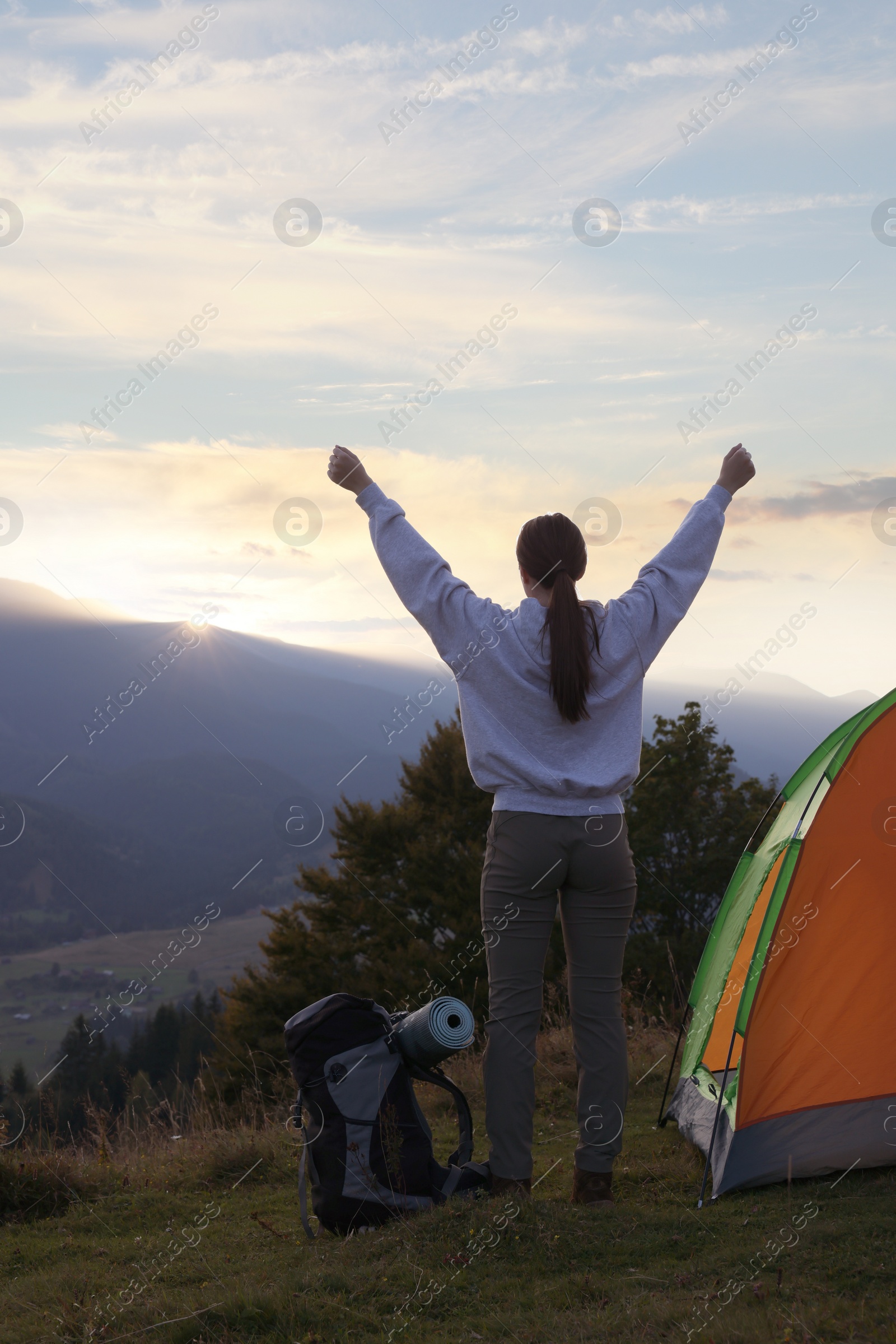 Photo of Tourist with backpack and sleeping pad near camping tent in mountains