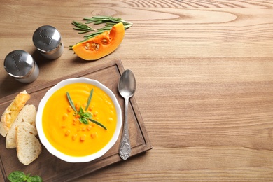 Photo of Flat lay composition with bowl of pumpkin soup and space for text on wooden background