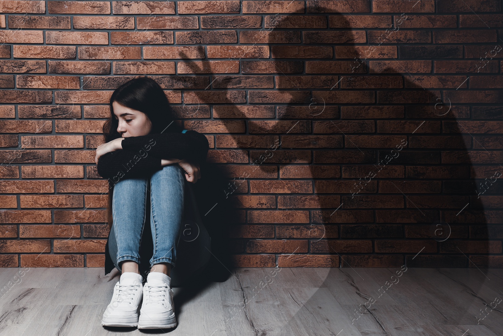 Image of Child abuse. Father yelling at his daughter. Shadow of man on brick wall