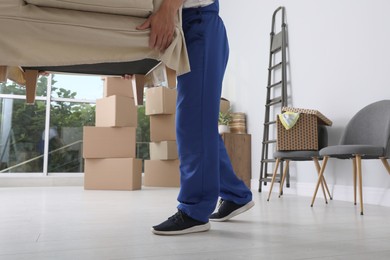 Photo of Moving service employee carrying armchair in room, closeup