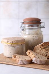 Photo of Sourdough starter in glass jars and fresh bread on light table