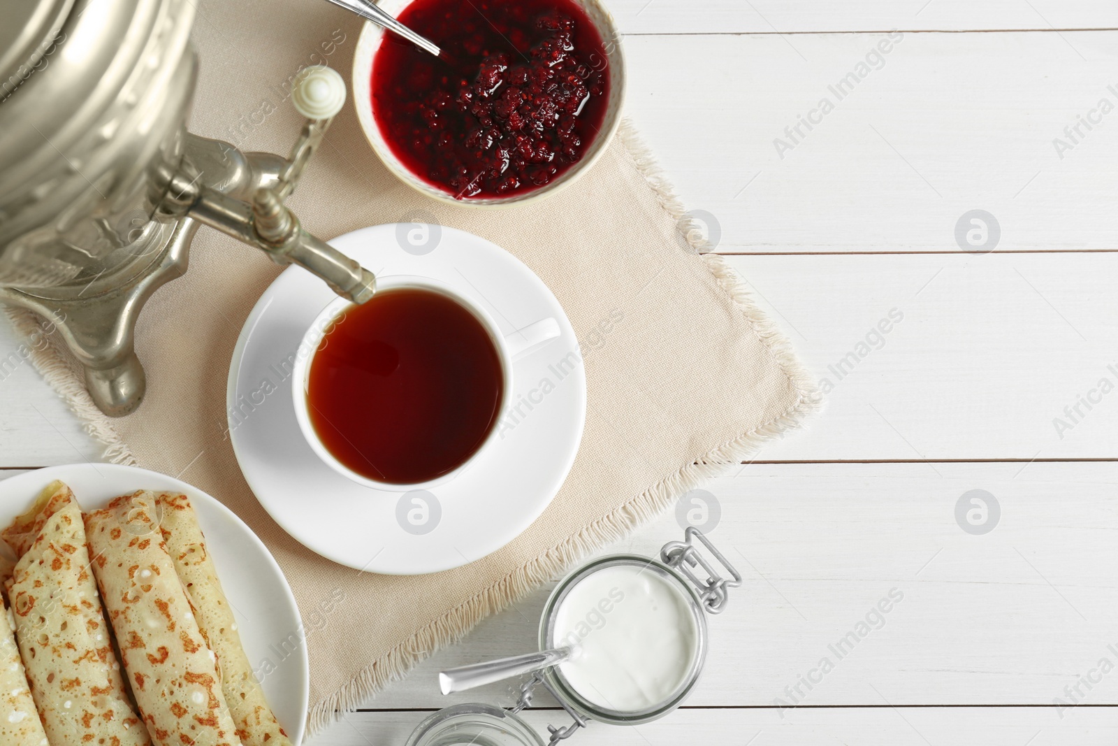 Photo of Vintage samovar, cup of hot drink and snacks served on white wooden table, flat lay with space for text. Traditional Russian tea ceremony