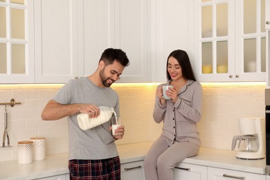 Happy couple in pajamas having breakfast at home