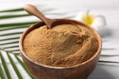 Photo of Coconut sugar and spoon in bowl on white table, closeup