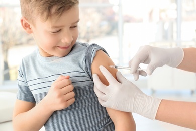 Doctor vaccinating little boy in hospital