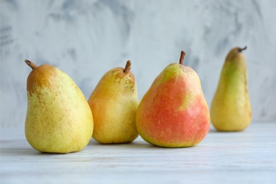 Photo of Juicy pears on white table against light background