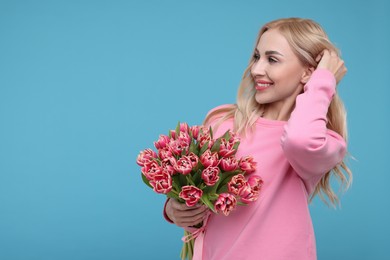 Beautiful young woman on light blue background